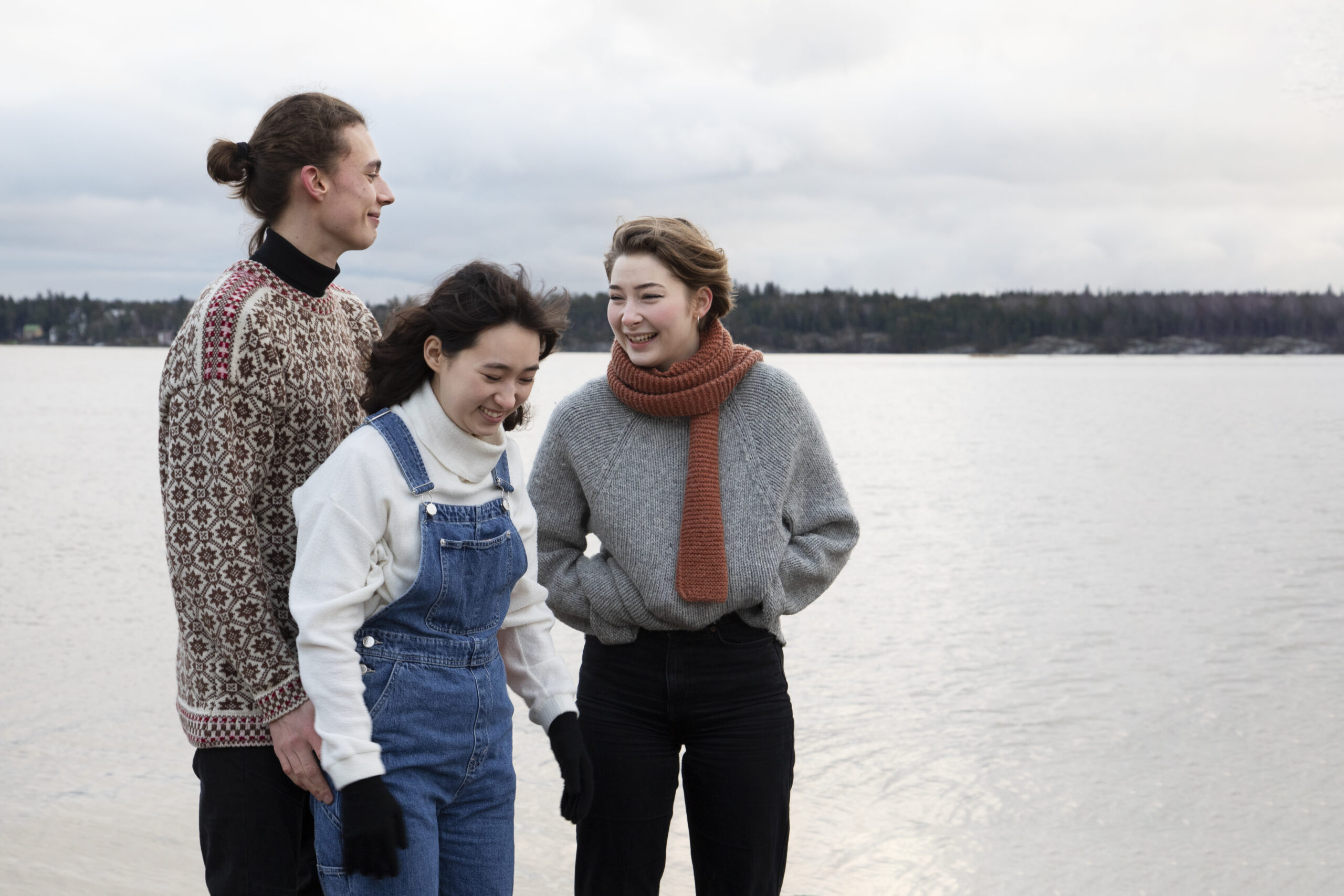 Kolme henkilöä järvimaiseman edessä kuvattuna